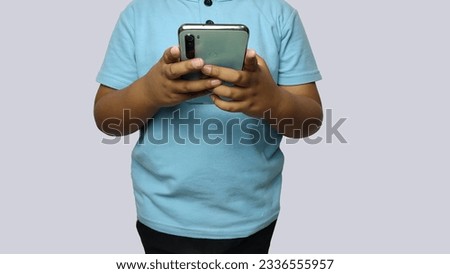 a fat kid in a light blue shirt is holding a cell phone