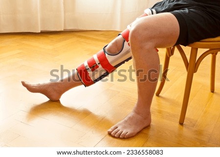 Adjustable knee immobilizer or leg brace on a male patient, used for fixation of the knee joint as treatment in case of fracture or ligament rupture. Royalty-Free Stock Photo #2336558083