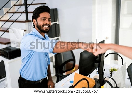 Cheerful Indian businessman partners making fist bump with a smile as a symbol of teamwork. Positive multi-ethnic business colleagues on diversity in the office. Collaboration concept