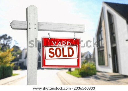Yard sale sign with Sold sticker near house