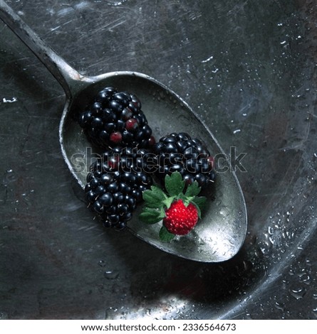 Fresh berries and old silver spoons on dark background , vintage close up photography