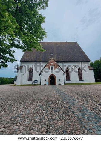 Wide Angle shot of Porvoo church. White church on a cloudy Day. Picture with a church and a tree. Gobble Stone pavement in front of a chappel. Old Euroopan architecture