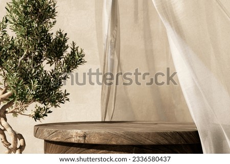 Natural wooden table and organic cloth with olive tree plant. Product placement mockup design background. Outdoor tropical summer scene with rustic vintage countertop display. Royalty-Free Stock Photo #2336580437