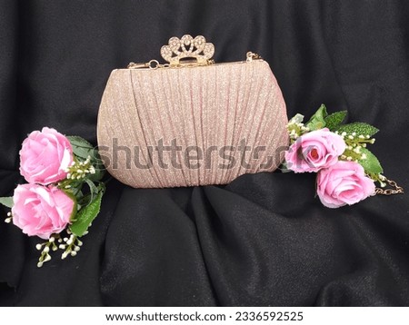 Stylish women's pink bag with rose isolated on a black background.Side View Luxury Women's Party Bag.With a Removable shoulder strap in shiny gold looks elegant it is perfect for party events.