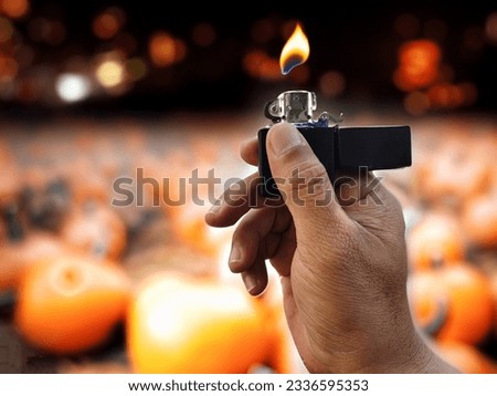 hand holding a match to light a pumpkin lantern on Halloween night.