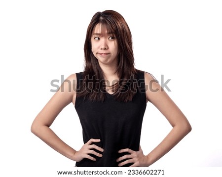 A portrait of Indonesian Chinese (Asian) woman in a black sleeveless shirt, making a little smirk as she is looking to her left. Skeptical concept. Isolated in a white background Royalty-Free Stock Photo #2336602271