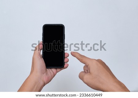 A man's hand pointing at a smartphone in his other hand