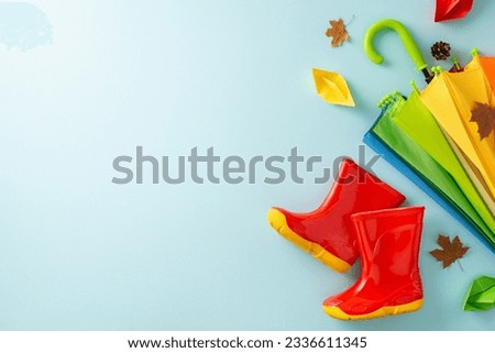 Enthralling autumn rain experience for children. Frame a top view picture exhibiting a colorful umbrella and rubber boots on light blue isolated background, inviting text or advert incorporation