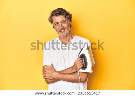 Man with iron in hand on a yellow background laughing and having fun.
