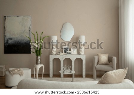 Warm and cozy living room interior with mock up poster frame, marble arch console, gray armchair, vase with flowers, white sofa, mirror, boucle pouf and personal accessories. Home decor. Template.
