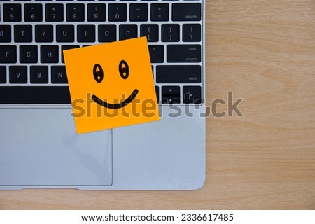 Symbol smile face paper color orange office laptop computer keyboard on table background.
Feedback employee team positive business,
World mental health day,