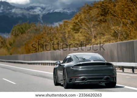 Elegant black modern two-door German roadster. Brand new black luxury carrera sports car on the highway. Royalty-Free Stock Photo #2336620263