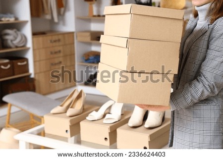 Woman holding paper boxes in light boutique, closeup