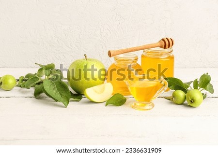 Jars and gravy boat of honey with apples for Rosh Hashanah celebration (Jewish New Year) on white wooden table Royalty-Free Stock Photo #2336631909