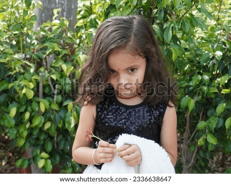 Clear face camera focus of blur background. Having fun in park with comedy action. Flower in hand looks so beautiful. Trees and plant around kid.It is using for wallpaper, street poster.