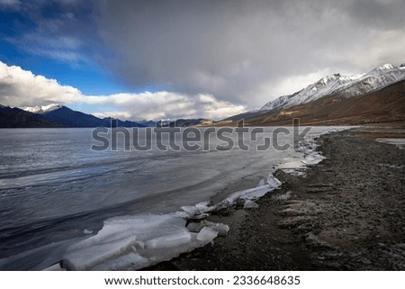 Icy formations, waves that appeared to be frozen in time on Pangong Lake's Shoreline, and mountains visible in the distance 