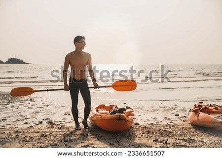Man kayaking at sunset sea, kayaking, canoeing, boating. Man playing on the beach with kayak at the day time. People having fun outdoors. Concept of summer vacation .