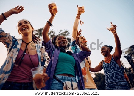Happy African American woman and her friends attending open air summer music festival.
