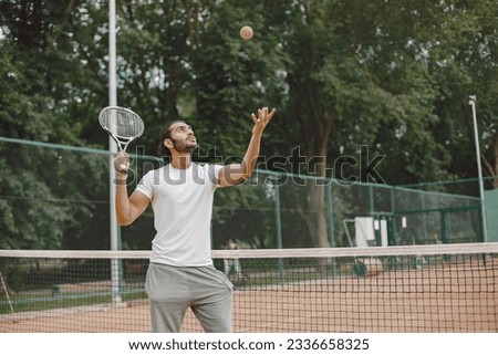 Indian male tennis player playing on the court outdoors
