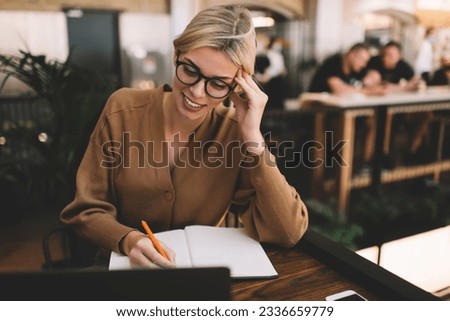 Smiling female student in spectacles watching education webinar while e learning in university, cheerful Caucasian woman in eyeglasses reading informative publication text while planning organization