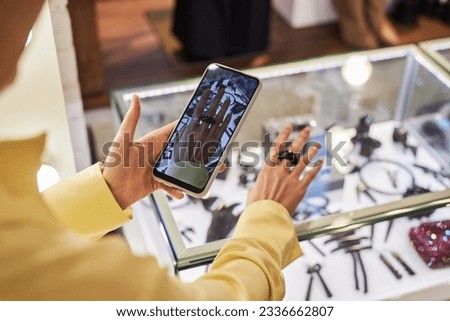 Closeup of young woman trying on rings and jewelry in boutique and taking photo for social media or promo pictures, copy space