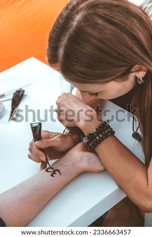Mehndi master drawing henna tattoo on female hand,mehendi art 