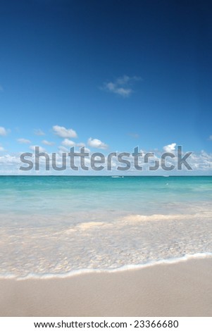 Beautiful Caribbean tropical beach with white sand and green ocean, suitable background for a variety of designs. FOCUS on edge of waves rolling onto the beach