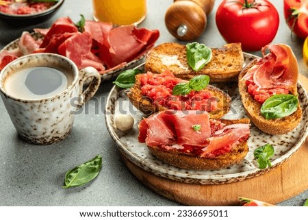 Spanish breakfast. Tostada with ripe tomato and ham jamon with coffee and juice. Royalty-Free Stock Photo #2336695011