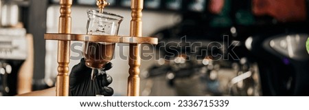 partial view of barista in black glove holding cold drip coffee maker with ground coffee, banner