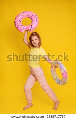 full height girl in yellow T-shirt mock up juggle with two inflatable rings in hands isolated over yellow background