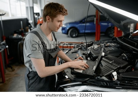 Mechanic providing computer diagnostics to find cause of car failure Royalty-Free Stock Photo #2336720311