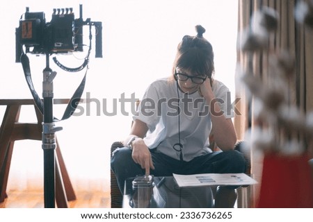 The director is a woman at work on the set. The director works with a group or with a playback while filming a movie, advertising, or a TV series. Shooting shift, equipment and group. 