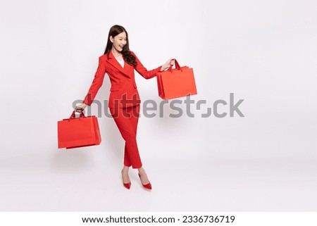 Young beautiful Asian businesswoman in red suit smiling and holding red shopping bag isolated on white background, Full body composition Royalty-Free Stock Photo #2336736719