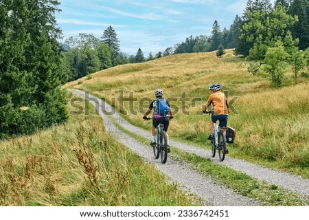 two senior girlfriends having fun during a cycling tour in the Allgau Alps near Oberstaufen, Bavaria, Germany Royalty-Free Stock Photo #2336742451