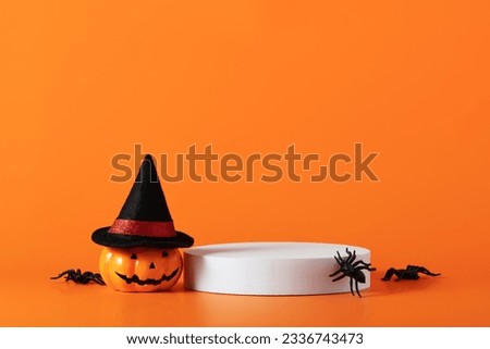 Creative Halloween composition with pumpkin, spiders, white podium and orange background. Modern Halloween aesthetic. Suitable for Product Display and Business Concept.