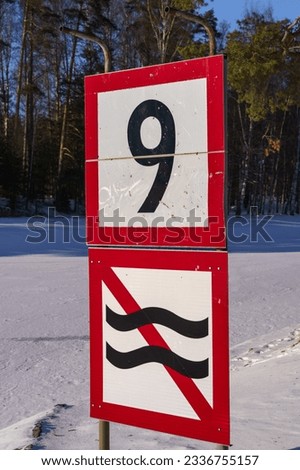 Speed limit and prohibition of causing waves sign next to a frozen river close up in Finland.
