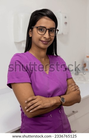 beautiful young female doctor with straight hair wears glasses and comfortable purple uniform, health professions, woman smiling
