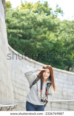 young woman who is taking pictures while traveling in Korea with a camera backpack