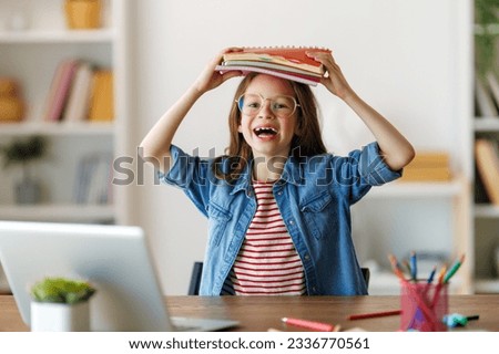 Back to school. Happy child is sitting at desk. Girl doing homework or online education. Royalty-Free Stock Photo #2336770561