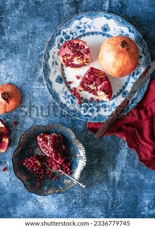 Peeled ripe pomegranate on a blue vintage dinner plate and blue background with red napkin