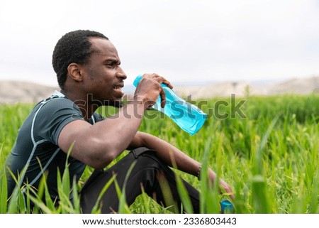 Fit young man in sportswear drinking water from a reusable metal bottle after running workout