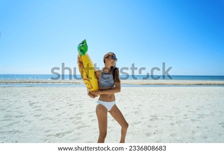Happy beach woman holding inflatable pineapple float ring against coastal backdrop. The vibrant colors, playful atmosphere at seashore Royalty-Free Stock Photo #2336808683