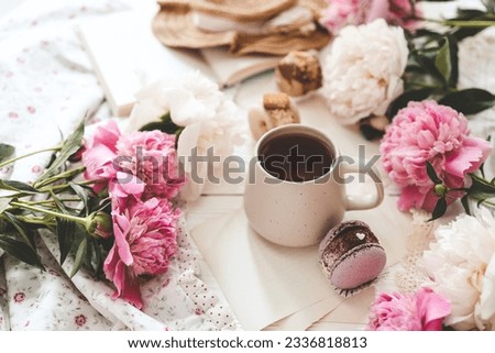 Cup of tea, macaroons and peonies, flat lay top view. good morning concept.