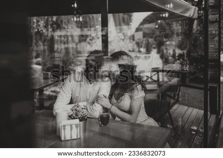 Side view portrait of a loving European couple laughing while enjoying a date in a cafe. Black and white photo