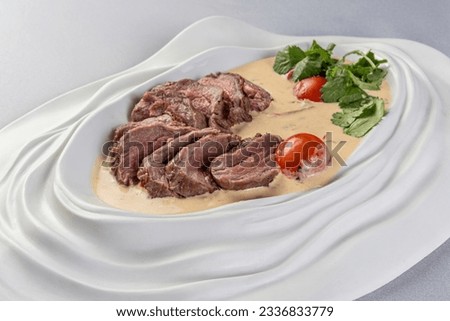 Dish of veal slices with sauce of tuna and capers.I italian vitello tonnato on a plate. Close up.