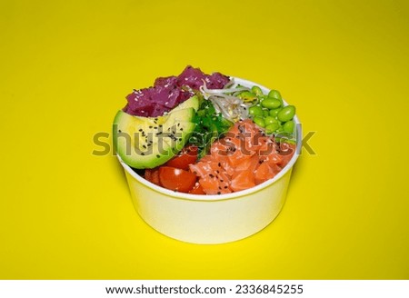 Fresh, healthy, colorful poke bowl on a yellow background with tuna fish, salmon seafood, edamame, wakame, avocado, soybean sprouts, and white rice