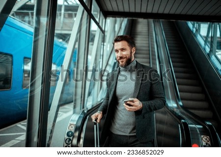 Young man using a smart phone while on an escalator at the train station