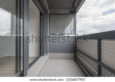 Terrace of a house with a gray fabric roller awning, gray aluminum and glass access glass and gray terrazzo floors