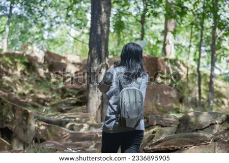 Woman trekking in summer, standing and taking pictures of natural scenery