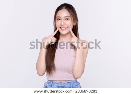 Beautiful young Asian woman pointing finger to her teeth on isolated white background. Facial and skin care concept for commercial advertising.